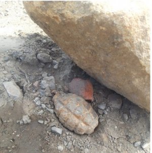 Na zdjęciu granat leżący pod dużym kamieniem