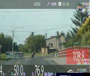Zdjęcie z policyjnego wideorejestratora znajdującego się we wnętrzu radiowozu, na którym widać jadący z dużą prędkością samochód.