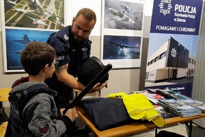Na zdjęciu policjant prezentuje sprzęt policyjny chłopcu