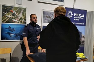 Na zdjęciu policjant rozmawia z mężczyzną przy stoliku profilaktycznym
