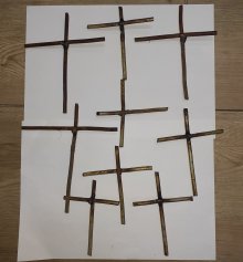 Na zdjęciu widać dziewięć metalowych prętów w kształcie krzyża rozłożonych na białym tle.