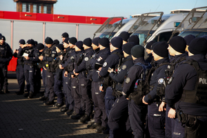 policjanci oddziału prewencji w trakcie odprawy na parkingu stoją w rzędzie