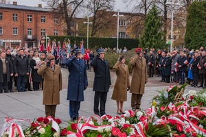 przedstawiciele służb mundurowych oddają honory w tle uczestnicy uroczystości