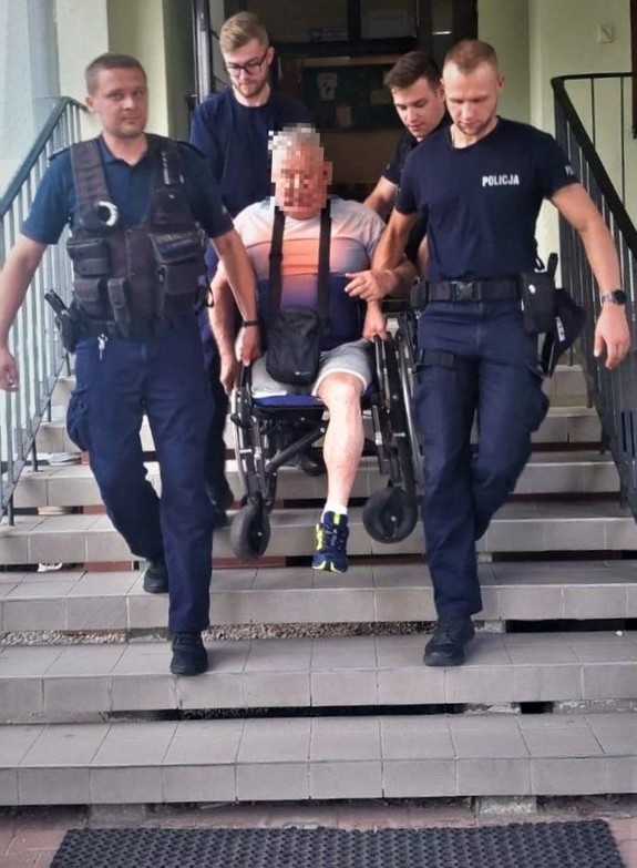 Policjanci znoszą ze schodów mężczyznę na wózku inwalidzkim