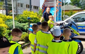 policjant z motocyklem i dzieci na policyjnym stoisku