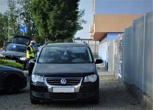 Policjant wykonujący czynności przy samochodzie