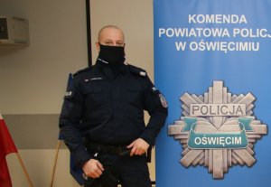 Na zdjęciu policjant obok roll upa z logo komendy Policji