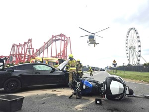 Motocykl i samochód na jezdni w tle park rozrywki