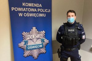 Na zdjęciu policjant w umundurowaniu na tle roll upa z gwiazdą policyjną