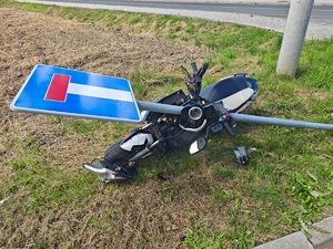 uszkodzony motocykl obok znaku
