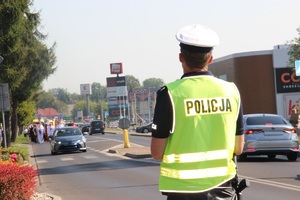 policjant zabezpiecza skrzyżowanie w oddali procesja