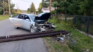 Na zdjęciu uszkodzony samochód obok lężący słup drewniany