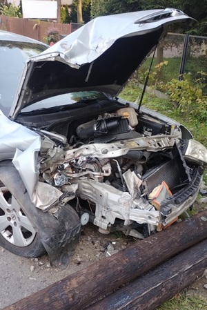 Na zdjęciu uszkodzony samochód obok lężący słup drewniany