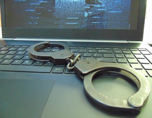 laptop na którym leżą kajdanki