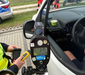policjant z miernikiem i alkoblow  przy samochodzie