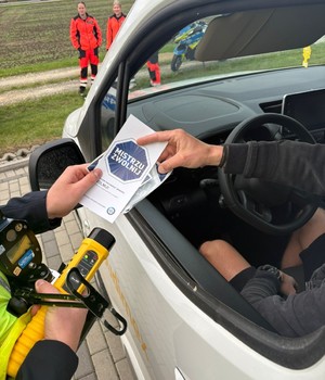 policjant wręcza ulotkę kierowcy