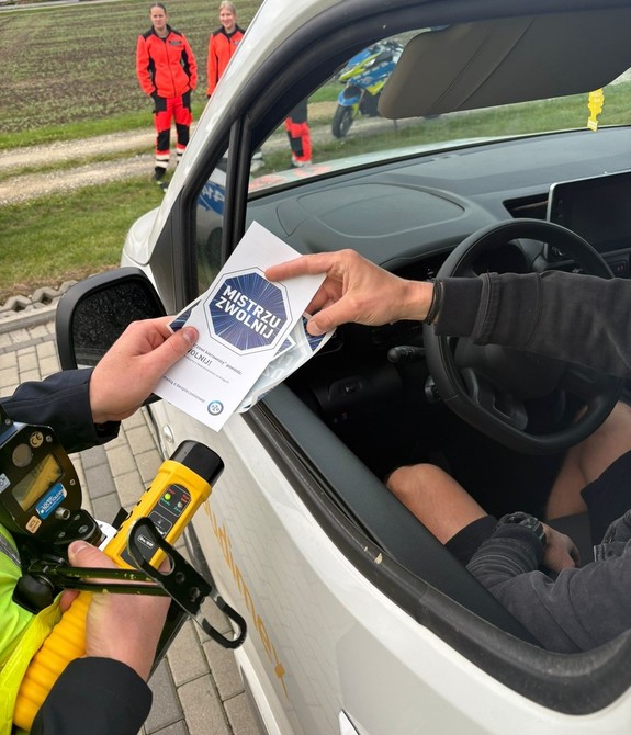 policjant wręcza ulotkę kierowcy