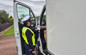 policjant wręcza ulotkę kierowcy dostawczaka