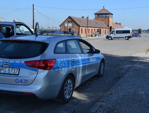 radiowóz na tle Bramy Śmierci w Birkenau