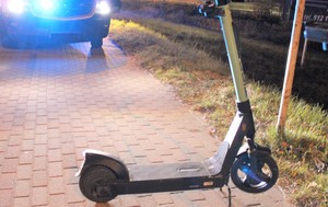 hulajnoga na chodniku w tle radiowóz