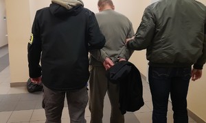 Zatrzymany mężczyzna obok dwaj policjanci