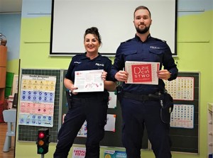 policjantka i policjant z plakatami kampanii w rękach