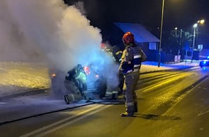 Zadymiony samochód na ulicy strażacy gaszą pojazd