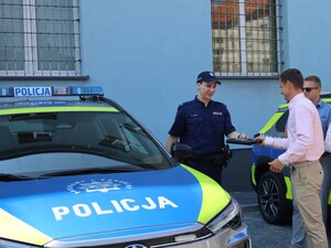 Na zdjęciu przekazywane radiowozy, przedstawiciele policji i gmin