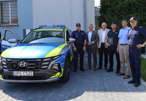 Na zdjęciu przekazywane radiowozy, przedstawiciele policji i gmin