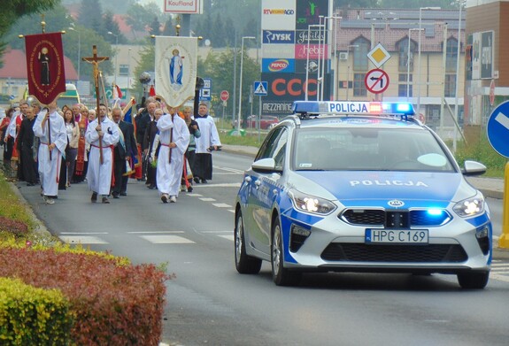 Na zdjęciu radiowóz procesja w tle