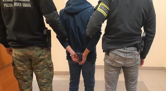 na zdjęciu strażnik graniczny i policjant z zatrzymanym obcokrajowcem