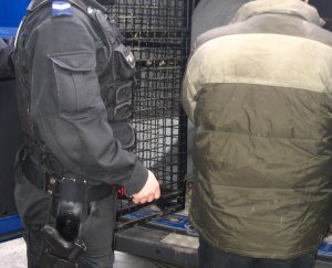 Na zdjęciu policjant z zatrzymanym mężczyzną przy radiowozie