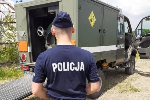 na zdjęciu policjant a w tle wóz saperów