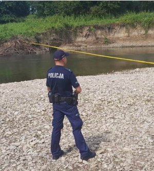 Policjant nad rzeką w tle zarośla