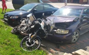 Na zdjęciu uszkodzony motocykl na maskach dwóch samochodów.