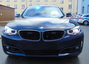 Na zdjęciu samochód BMW nieoznakowany z włączonymi sygnałami. W tle bloki mieszkalne i pojazdy.