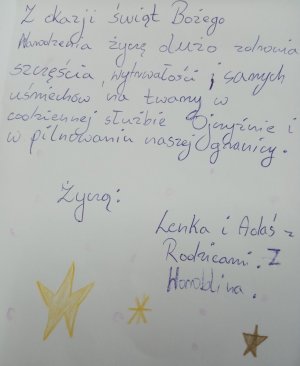 Kartka z napisem odręcznym „… dużo zdrowia, szczęścia wytrwałości i samych uśmiechów na twarzy w codziennej służbie Ojczyźnie i pilnowaniu naszej granicy, życzą Lenka i Adaś z rodzicami”