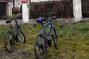Na zdjęciu dwa rowery stojące przy płocie