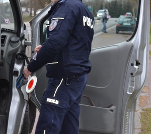 Na zdjęciu policjant przy samochodzie dokonuje kontroli drogowej
