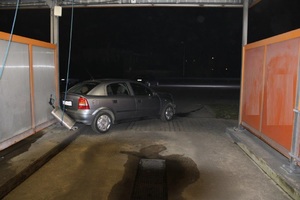 Na zdjęciu widać noc. Samochód z uszkodzonym tyłem stoi przy wiacie myjni.