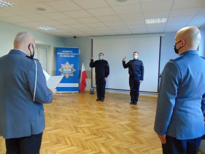 Na zdjęciu dwóch policjantów z uniesionymi prawymi rękoma do ślubowania.