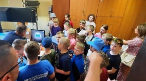 technik kryminalistyki prezentuje dzieciom komputer i sprzęt do skanowania odcisków palców