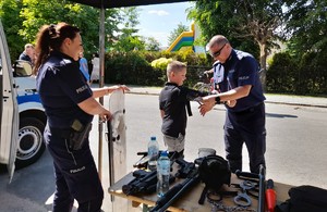 policjant zakłada dziecku umundurowanie obok stoi policjanka
