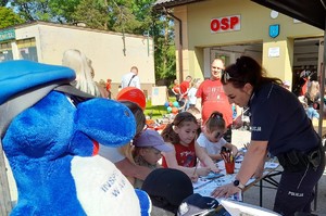 policjantka pomaga dzieciom w kolorowaniu na stoisku maskotka Inspektora Wawelka