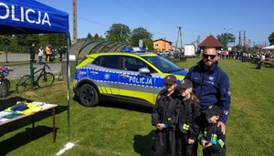 policjant z dziećmi za nimi stoi radiowóz